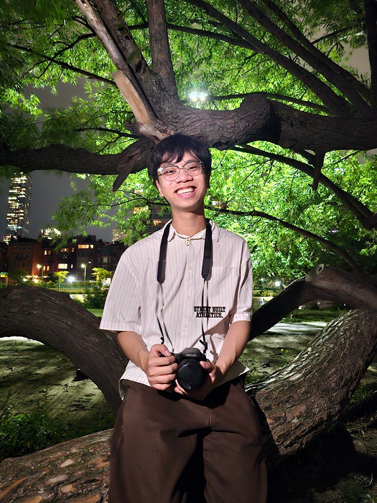 Image of young man sitting on the branch of a live oak at Rice University